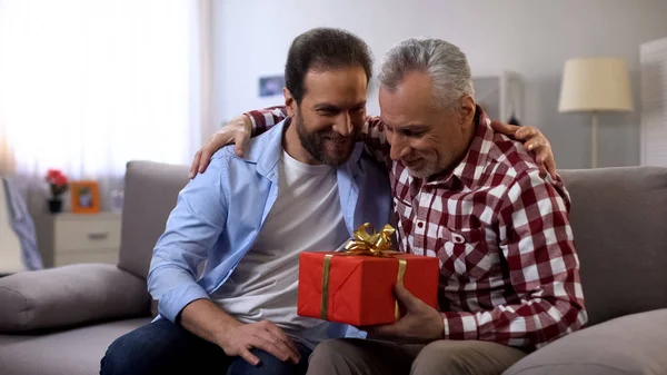 Son and father embracing, male holding gift box, receiving greetings, birthday