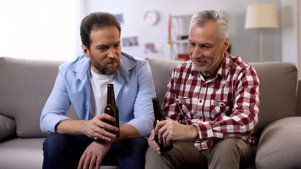 Father-in-law and son drinking beer and communicating, relax time, togetherness