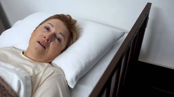身患绝症的高级女士哭着看着镜头 躺在临终关怀的床上 — 图库照片