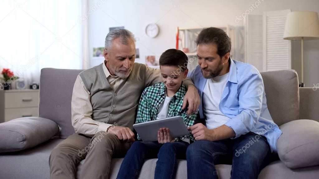 Grandfather and father scrolling tablet checking school marks in online register