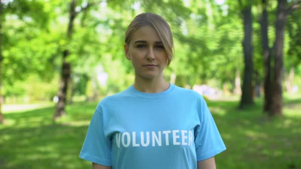 Femme blanche bénévole debout dans le parc souriant à la caméra, environnement — Video