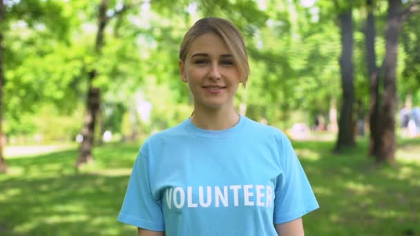 Mujer bonita joven señalando palabra voluntaria en camiseta azul, eco activista — Vídeo de stock