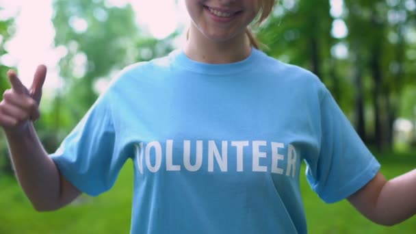 Fröhliche junge Frau zeigt auf freiwilliges Wort auf T-Shirt, Verantwortung — Stockvideo