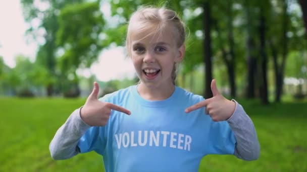 Happy schoolgirl pointing volunteer word on t-shirt, eco project participation — Stock Video