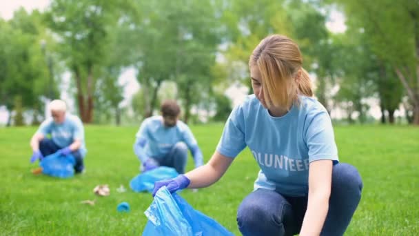 Mujer bastante sonriente recogiendo basura del bosque, voluntariado ambiental — Vídeo de stock