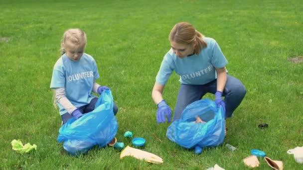 Iskoláslánya és anyja gyűjtése szemetet Park, föld szennyezés, az ökoszisztéma — Stock videók