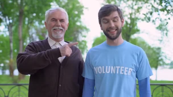 Rentner und Sozialaktivist zeigt auf freiwilliges Wort auf T-Shirt, Hilfe — Stockvideo