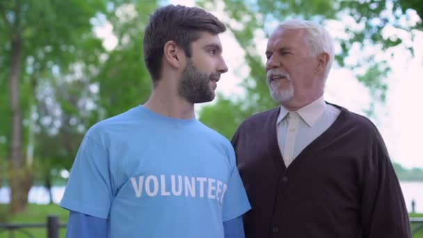 Ung manlig volontär och mogen gentleman leende till varandra, socialt stöd — Stockvideo