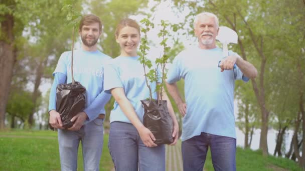 Ecologistas sonrientes sosteniendo árboles y palas en las manos, reforestación — Vídeos de Stock