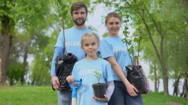 Eltern und Kind in freiwilligen T-Shirts mit Topfbäumen Naturschutz — Stockvideo