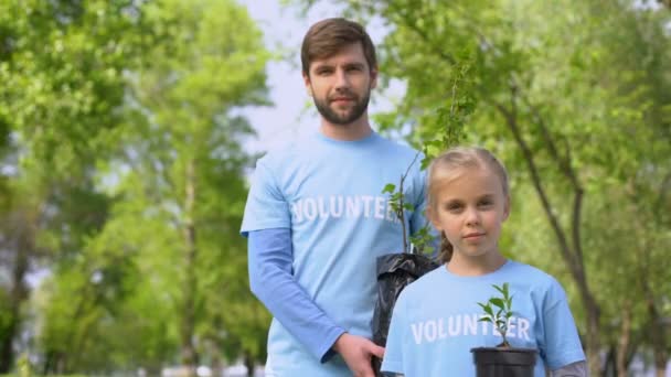Улыбающиеся отец и дочь держат саженцы зеленых растений, фонд восстановления лесов — стоковое видео