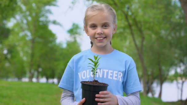 Ragazzo femminile allegro che tiene la pianta sorridente macchina fotografica, conservazione delle risorse naturali — Video Stock