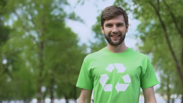 Hombre guapo en el símbolo de reciclaje camiseta mirando cámara, protección del medio ambiente — Vídeos de Stock