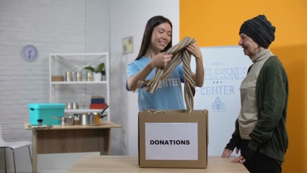Gelukkige vluchteling en vrijwilliger glimlachende camera, ontvangen kleren dakloos centrum — Stockvideo