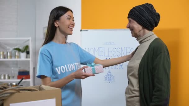 Voluntaria sonriente presentando caja de regalo a mujeres necesitadas, cuidado filantrópico — Vídeos de Stock