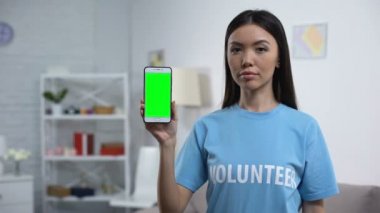 Akıllı telefon yeşil ekran gösteren Charity fon çalışanı, gönüllü uygulama, yardım