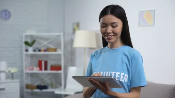 Voluntario alegre con la cámara sonriente tableta, aplicación de recaudación de fondos en línea — Vídeo de stock