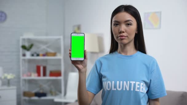 Φιλανθρωπικός εργαζόμενος που εμφανίζει πράσινη οθόνη smartphone, εφαρμογή εθελοντισμού, βοήθεια — Αρχείο Βίντεο