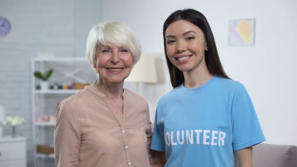 Glad äldre kvinna och volontär visar tummen upp leende på kamera, omsorg — Stockvideo