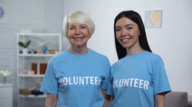 Neşeli genç ve olgun aktivistler başparmak gösteren, sosyal gönüllü hayır