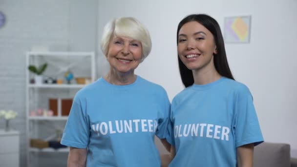 Volwassen en jonge vrouwen in vrijwilligers t-shirts glimlachend op camera, hulp — Stockvideo