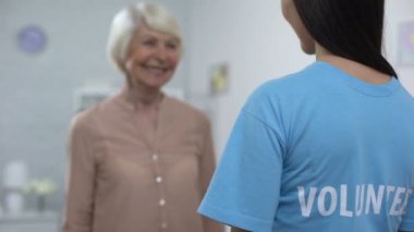 Genç kadın gönüllü kucaklayan gülümseyen yaşlı bayan, yaşlı bakım, huzurevi