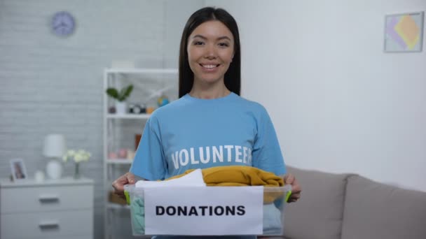Радісний громадський активіст тримає коробку пожертвувань з одягом, соціальне волонтерство — стокове відео