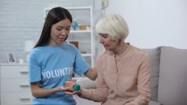 Sosyal hizmet uzmanı dambıl, rehabilitasyon ile egzersiz yapan yaşlı kadına yardım