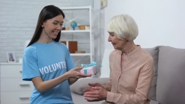Mujer trabajadora social dando regalo sonriente señora anciana, saludo de cumpleaños, cuidado — Vídeo de stock