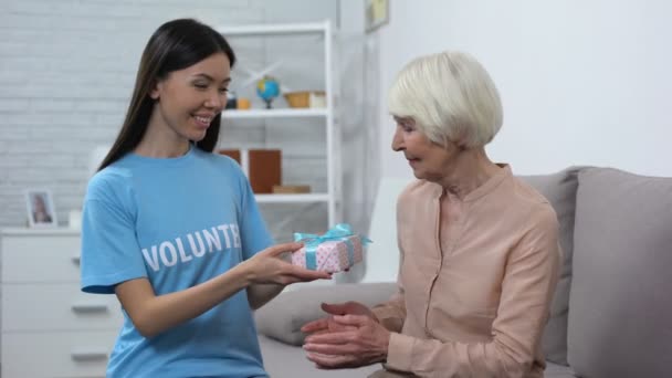 Mulher assistente social dando presente sorridente senhora idosa, cumprimento de aniversário, cuidado — Vídeo de Stock