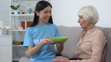 Kadın sosyal aktivist kanepede olgun bayan için akşam yemeği tabağı veren, gönüllü