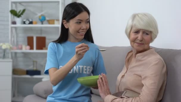 Mujer anciana molesta que se niega a comer avena ofrecida por un voluntario, un hogar de ancianos — Vídeos de Stock