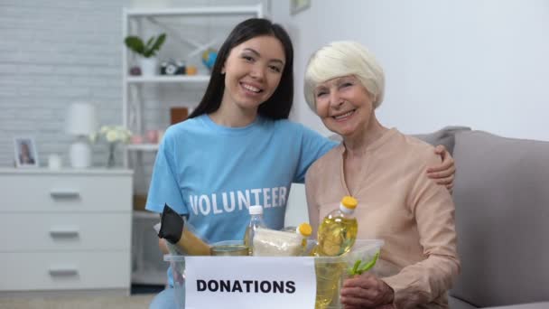 Заботливый активист обнимает пенсионерку с коробкой для пожертвований, поддерживает — стоковое видео