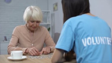 Kadın emekli genç gönüllü bir araya bulmaca koyarak, yaşlı insanların dikkat
