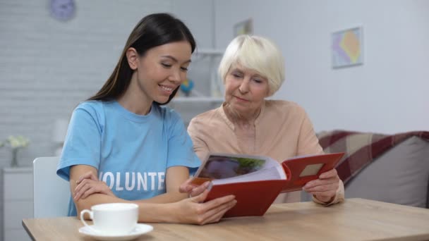 Social activist and female pensioner viewing album photos together, attention — Stock Video