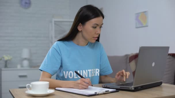 Trabajador social lista de escritura portátil de trabajo y sonriendo en la cámara, fondo de caridad — Vídeo de stock