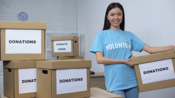 Молодой улыбающийся активист держит коробку для пожертвований, центр волонтеров, благотворительность — стоковое видео