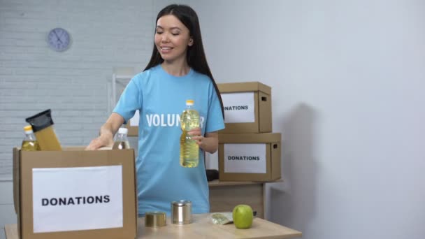 Счастливая женщина-волонтер кладет еду в коробку для пожертвований, благотворительный фонд — стоковое видео