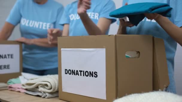 Εθελοντές του κοινωνικού κέντρου που βάζουν ρούχα σε κουτιά δωρεών, αλτρουισμός γενναιοδωρία — Αρχείο Βίντεο