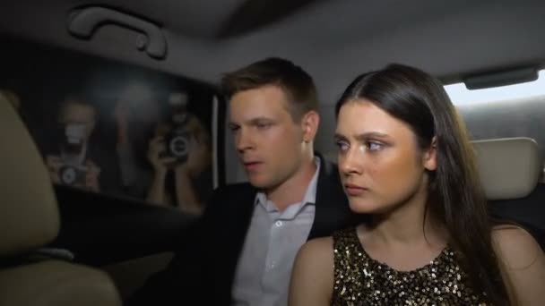 Triste couple de célébrités assis dans la voiture, cachant le visage des caméras paparazzi, commérages — Video
