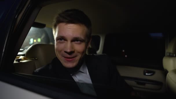 Όμορφος ηθοποιός κοιτάζοντας το κοινό από το πίσω κάθισμα του αυτοκινήτου, απολαμβάνοντας ταινία Premier party — Αρχείο Βίντεο