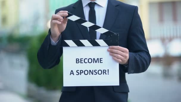 Become a sponsor phrase on clapperboard in hands of producer, independent movie — Stock Video