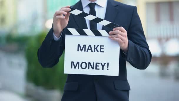 Hacer frase de dinero en clapperboard en manos de empresario exitoso, taller — Vídeo de stock