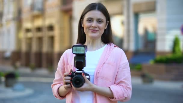 Sonriente joven de pie con la cámara en la calle de la ciudad, lecciones de fotografía — Vídeo de stock