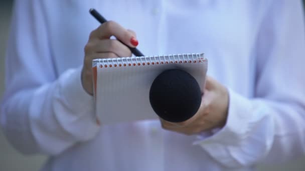 Periodista con micrófono escribiendo datos en cuaderno, preparando artículo periodístico — Vídeos de Stock