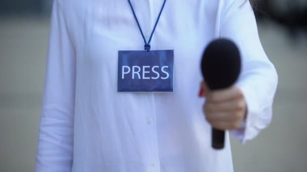 Gazeteci basın kimliği ile röportaj için mikrofon öneren, televizyon haberleri — Stok video
