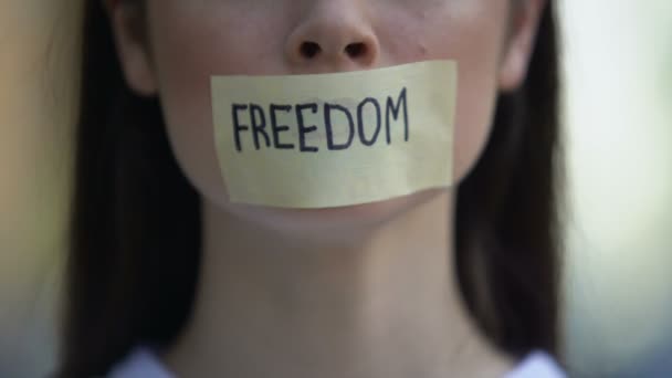 Леди снимает ленту со свободой слова в рот, протестует против дискриминации — стоковое видео