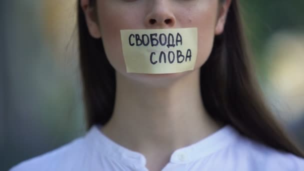 Donna che toglie il nastro con la libertà di parola frase in russo sopra la bocca — Video Stock