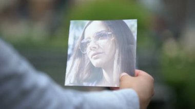 Kadın fotoğrafı tutan adam, bankta konuşan kızı izliyor,