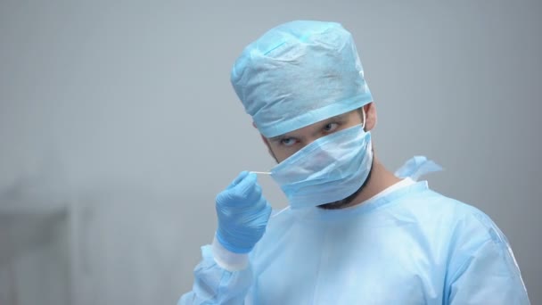 Professional surgeon in uniform wearing medical face mask before operation — Stock Video